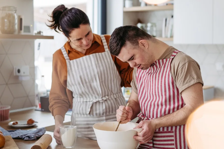 Disabled man cooking in kitchen with support worker