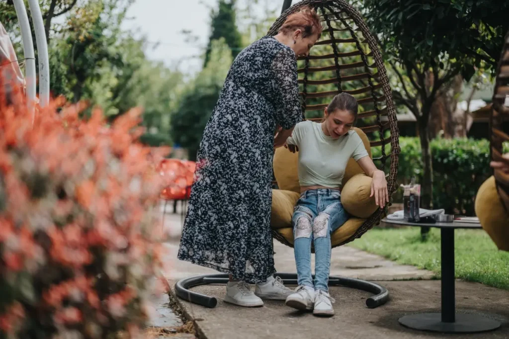 Support worker helping disabled girl sit in egg chair