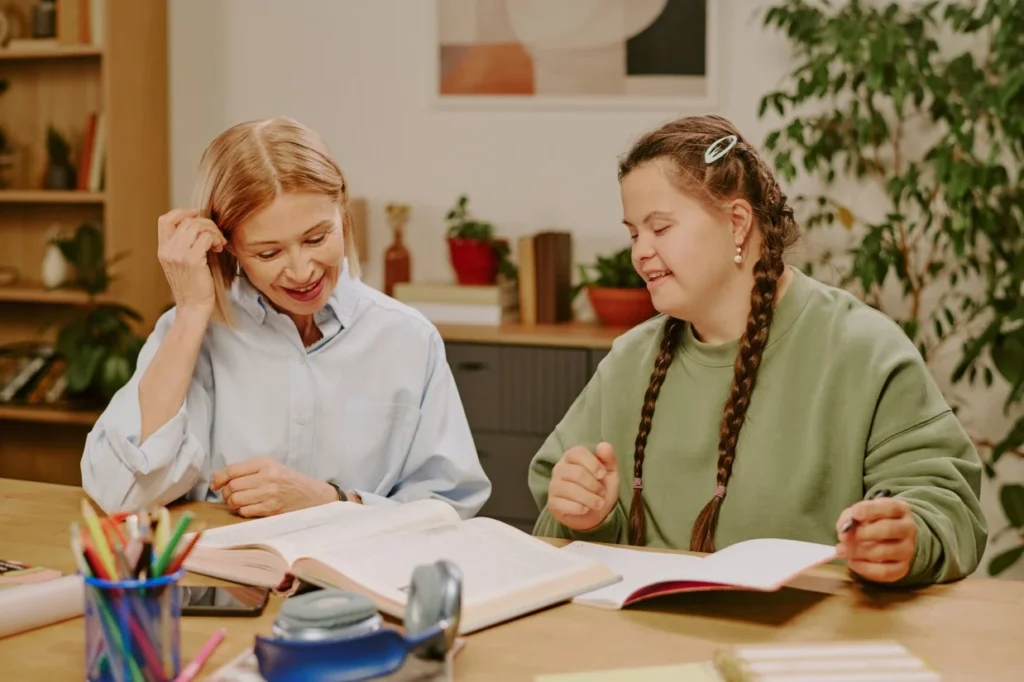 Disabled woman with down syndrome reading book with support worker